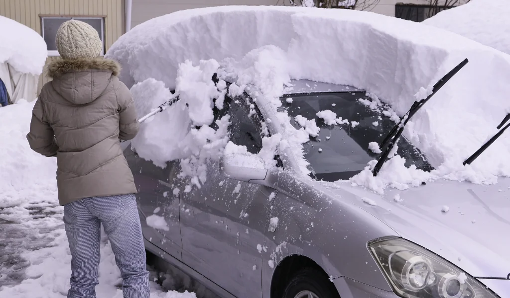 車の雪かきをする女性