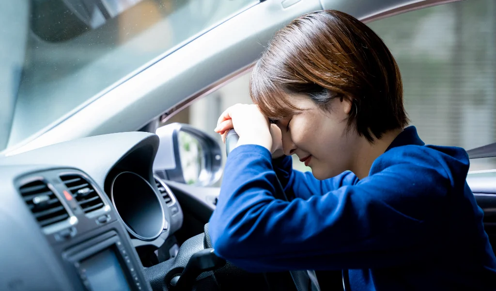 車の運転席でうなだれる母親