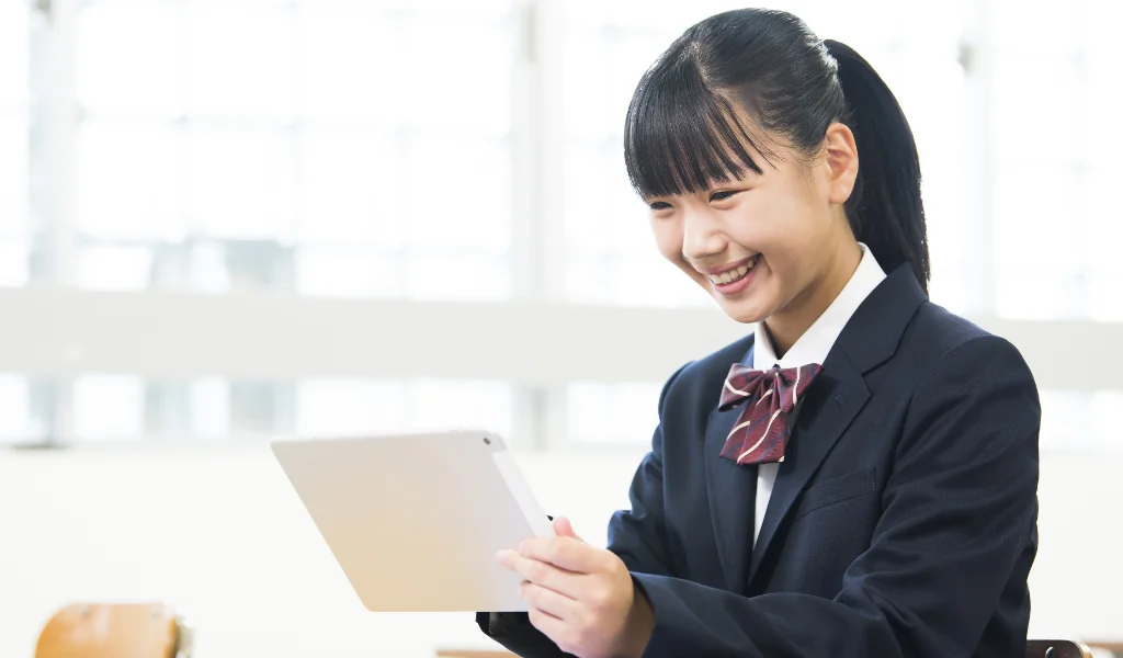 笑顔でタブレットで授業を受ける女子中学生