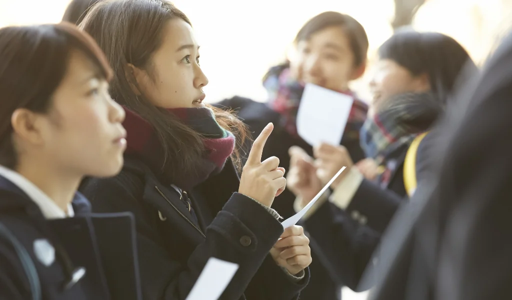不安な表情で合格発表を見つめる女子高生